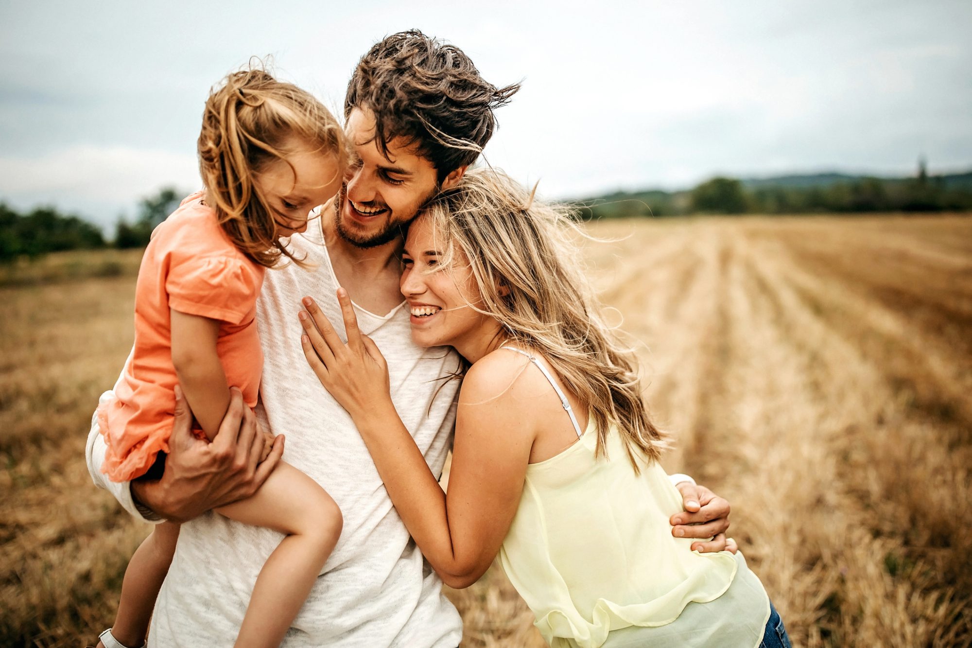 An image of a married couple embracing with their daughter.