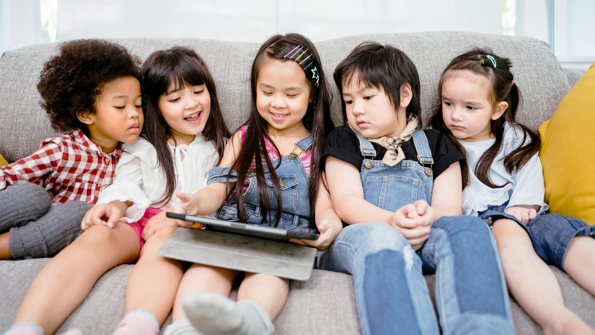 children on sofa using tablet