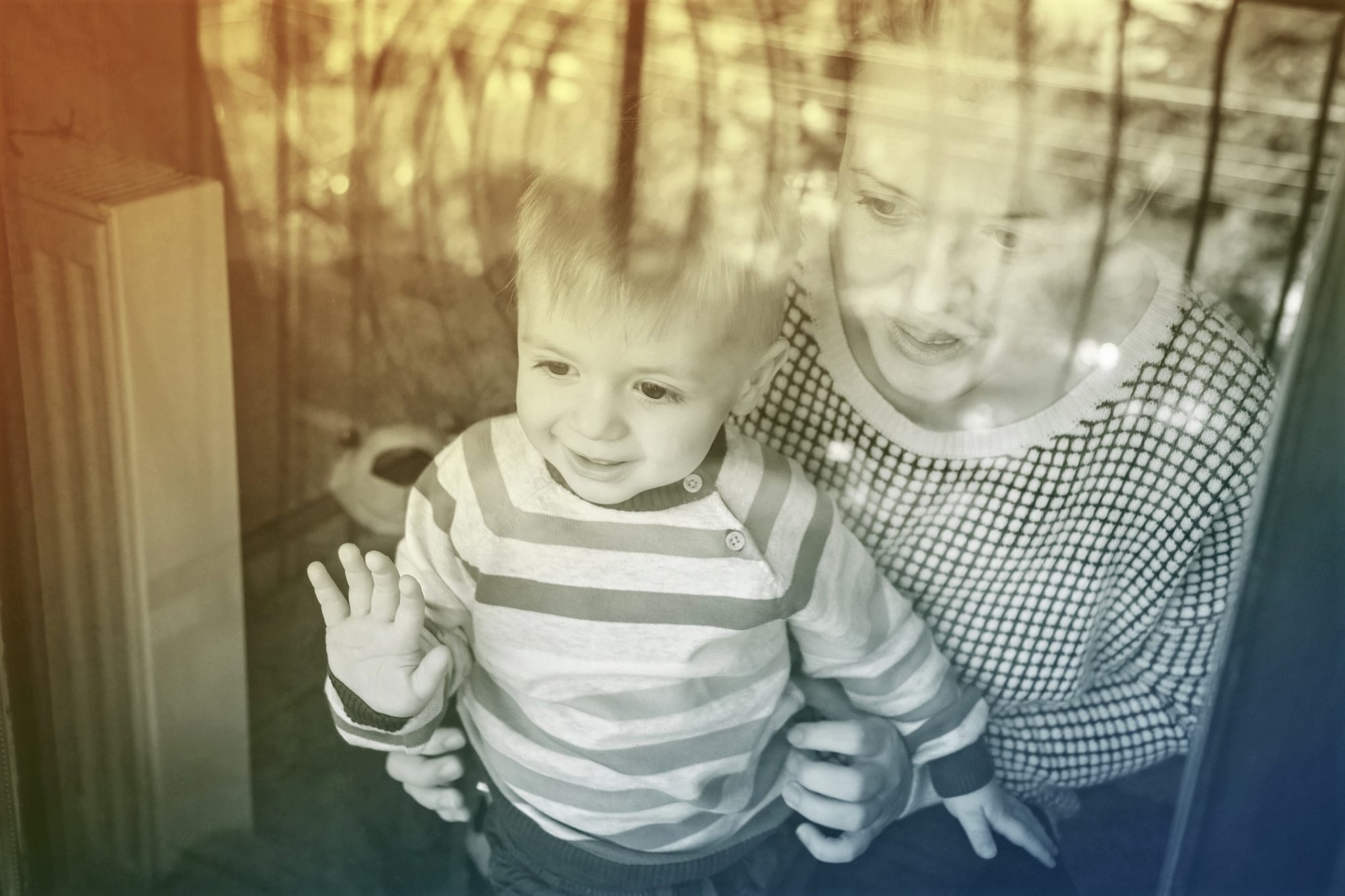 mother and little boy stand near window at home