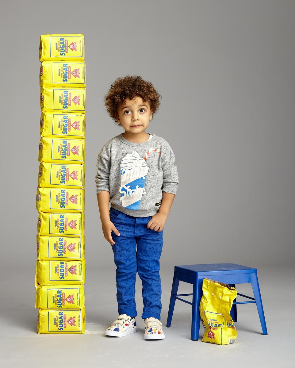 Curly Haired Boy Next to Bags of Sugar