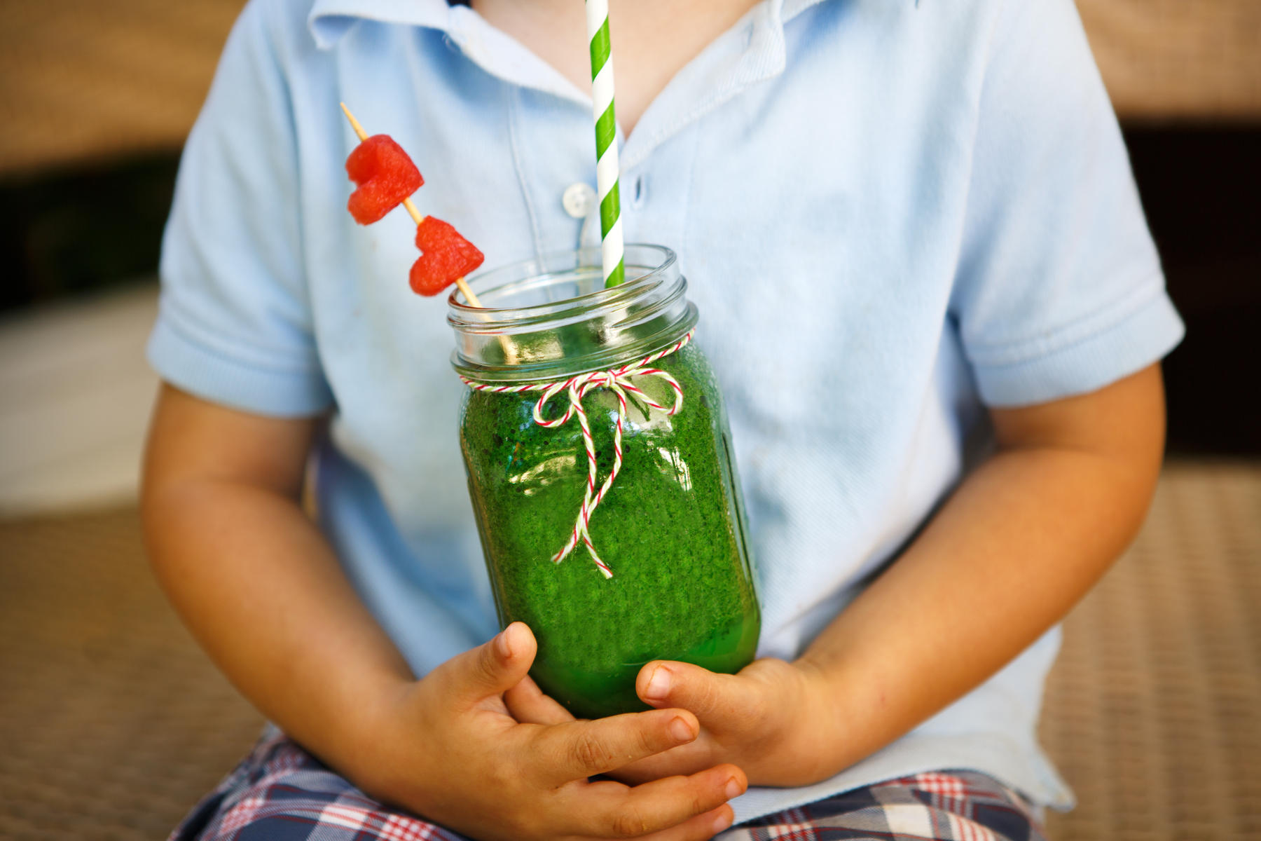 boy holding green smoothie with heart straw