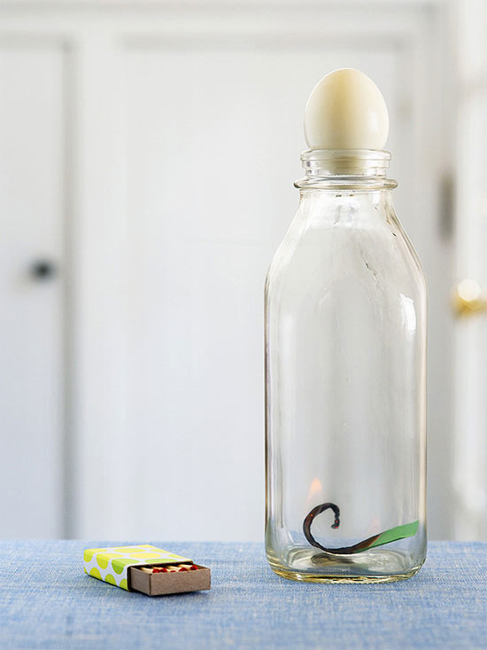 Glass bottle with flame inside and egg on top