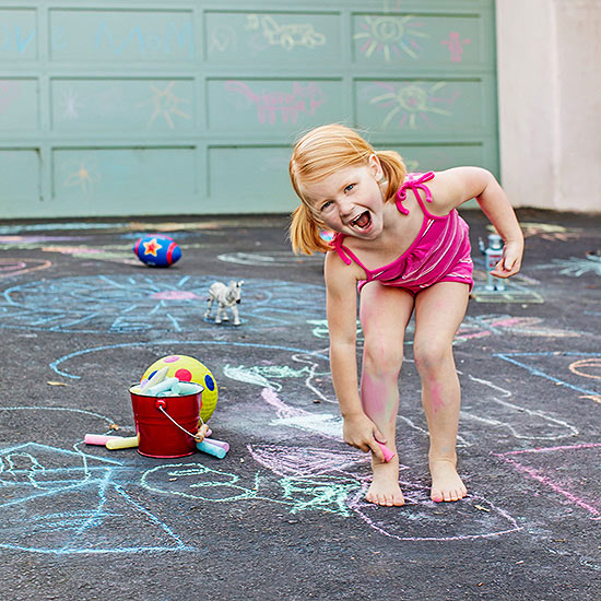 child playing with chalk in driveway