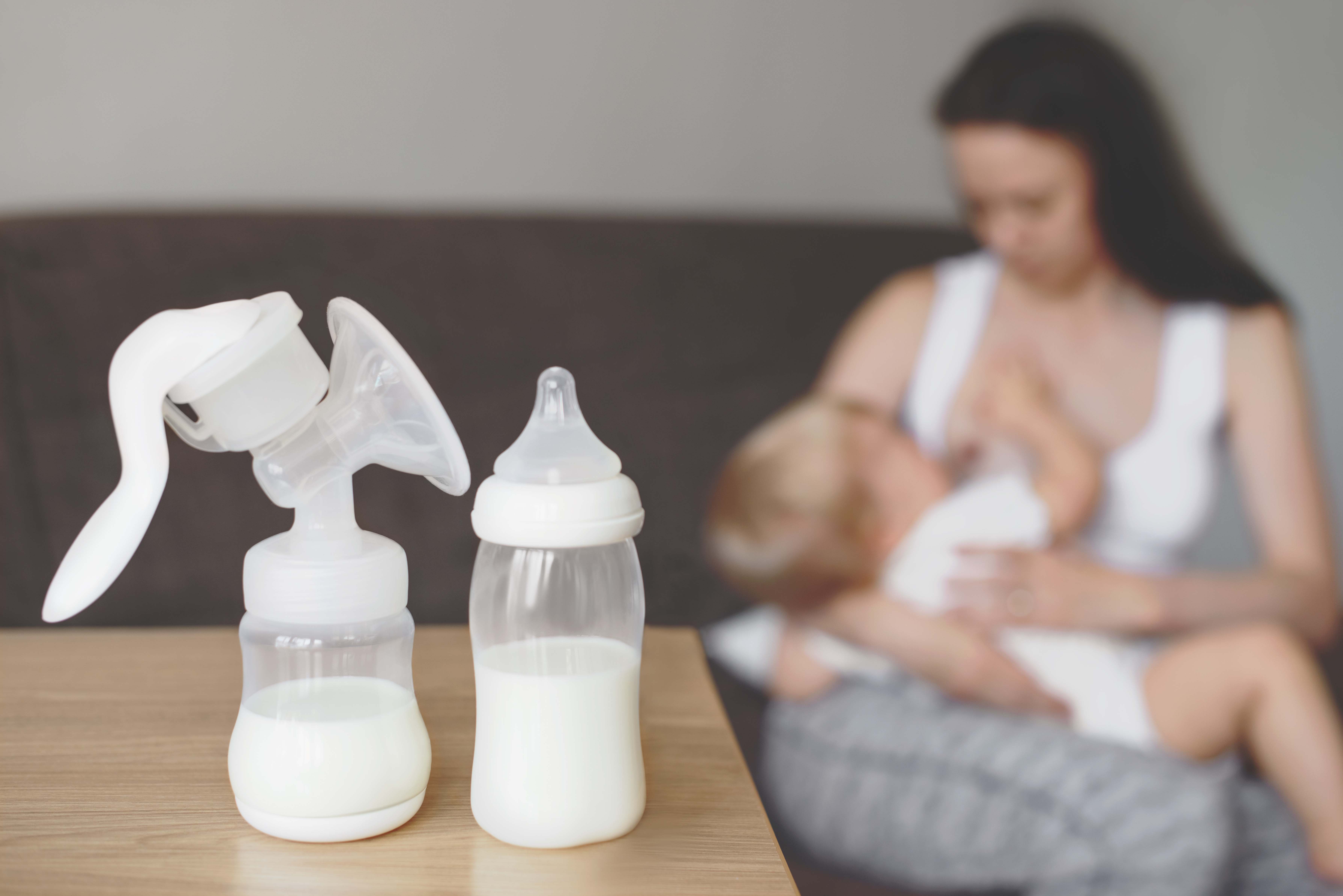 breastmilk bottles with mom feeding in background